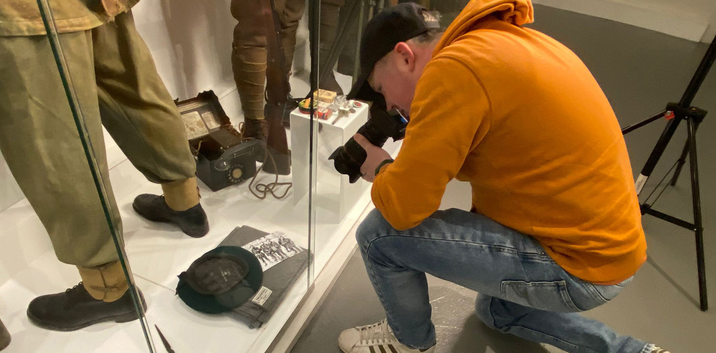 Een filmer van MuseumTV maakt opnames van een vitrine met militaire voorwerpen bij Polderhuis Westkapelle.