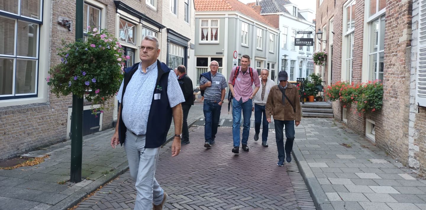 Deelnemers aan de Erfgoedvrijwilligersdag wandelen tijdens een excursie in Tholen onder leiding van een gids.