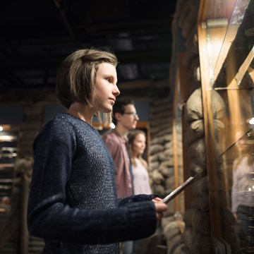 Een jeugdige museumbezoeker bekijkt aandachtig de vitrine