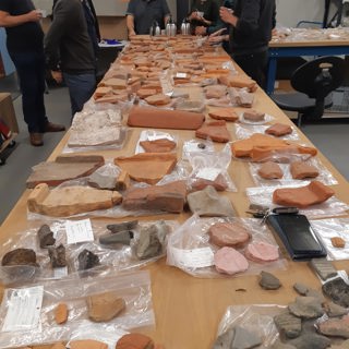 Strandvondsten van het project Beach Archaeology in de uitlegruimte van het depot, met onderzoekers eromheen.