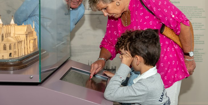 Kinderen maken een opdracht in het Stadsmuseum in Zierikzee, twee bezoekers helpen mee.
