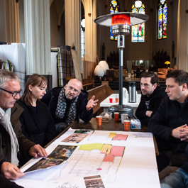 Deelnemers aan het maandelijkse Planoverleg vergunningen in een kerkgebouw.