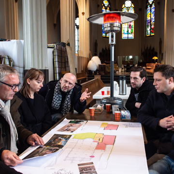 Deelnemers aan het maandelijkse Planoverleg vergunningen in een kerkgebouw.