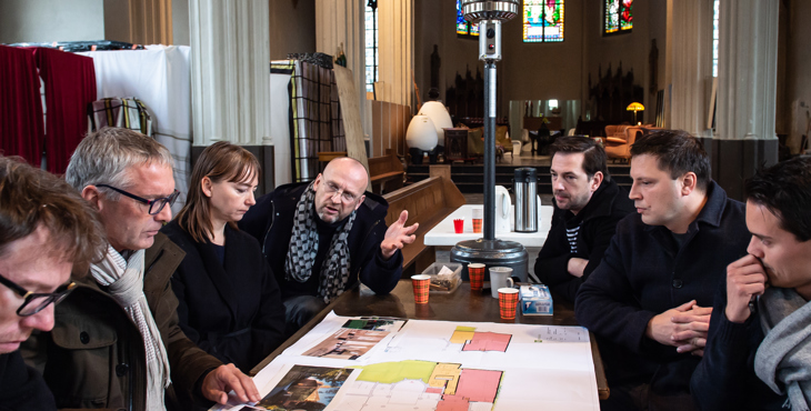 Deelnemers aan het maandelijkse Planoverleg vergunningen in een kerkgebouw.