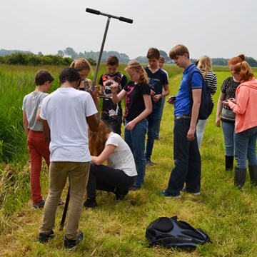 Een klas leert van een archeoloog hoe je moet werken met een grondboor aan de Kievitshoekweg in Grijpskerke.