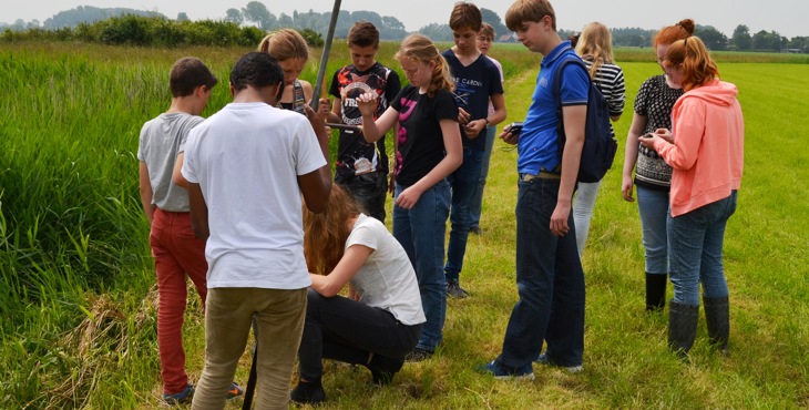 Een klas leert van een archeoloog hoe je moet werken met een grondboor aan de Kievitshoekweg in Grijpskerke.