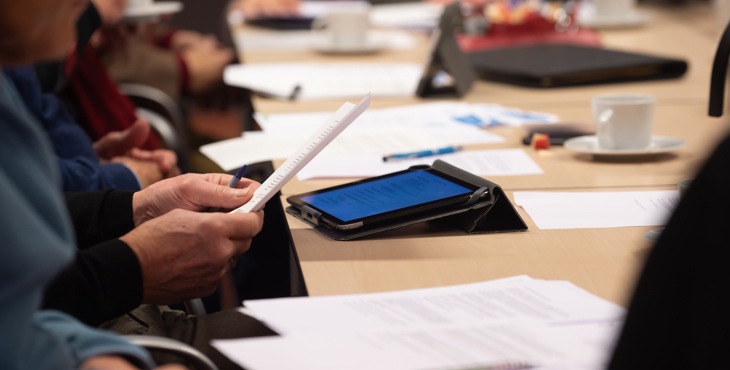 Mensen aan een vergadertafel met papieren en tablets