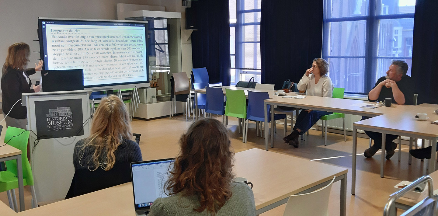 Trainer en deelnemers van de cursus Tentoonstellingsteksten schrijven in een leslokaal.