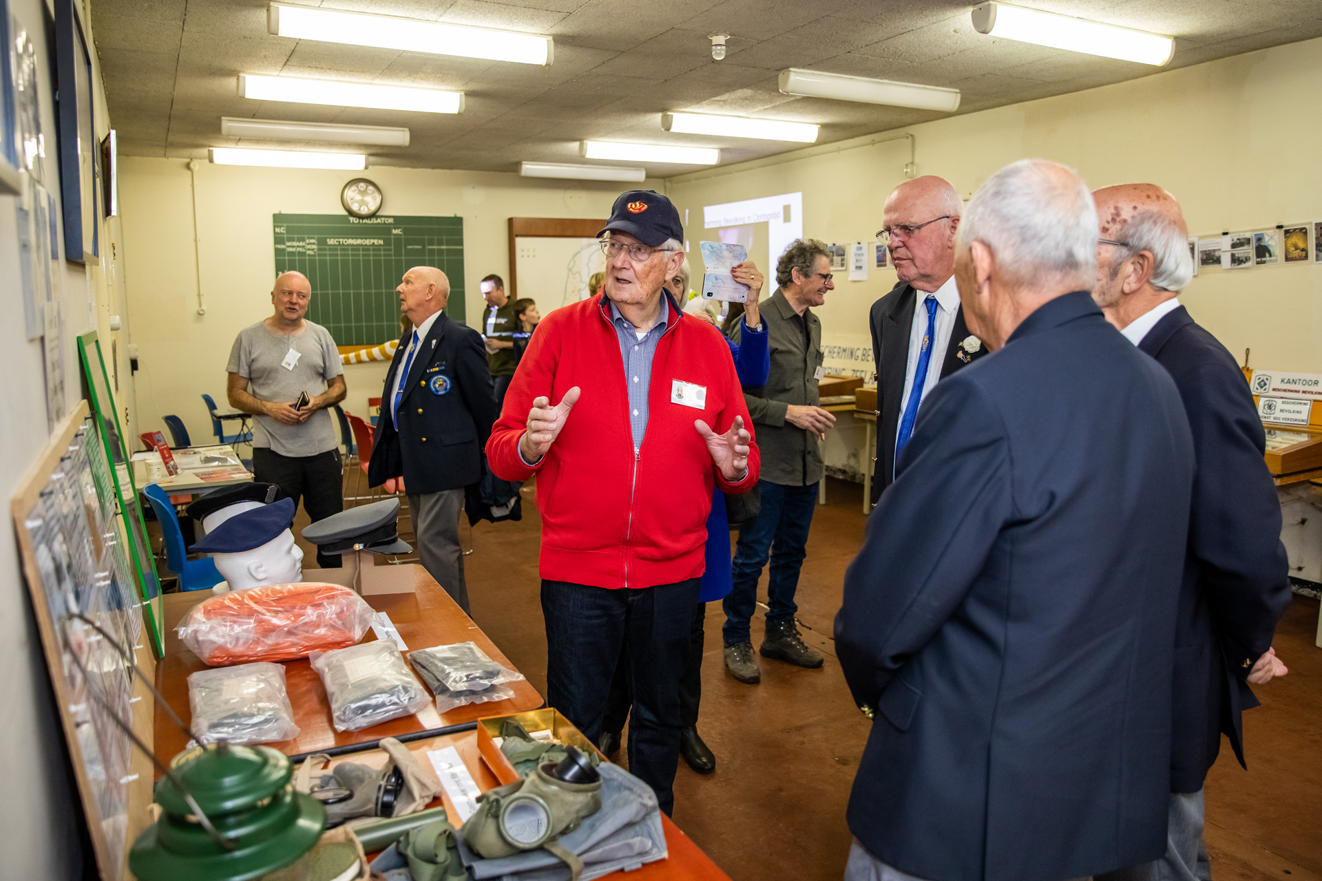 Vrijwilliger geeft uitleg aan mannen in uniform in BB-bunker.