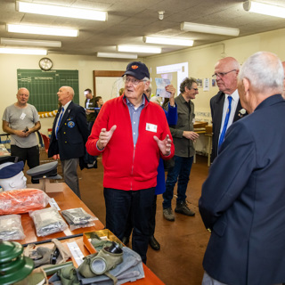 Vrijwilliger geeft uitleg aan mannen in uniform in BB-bunker.