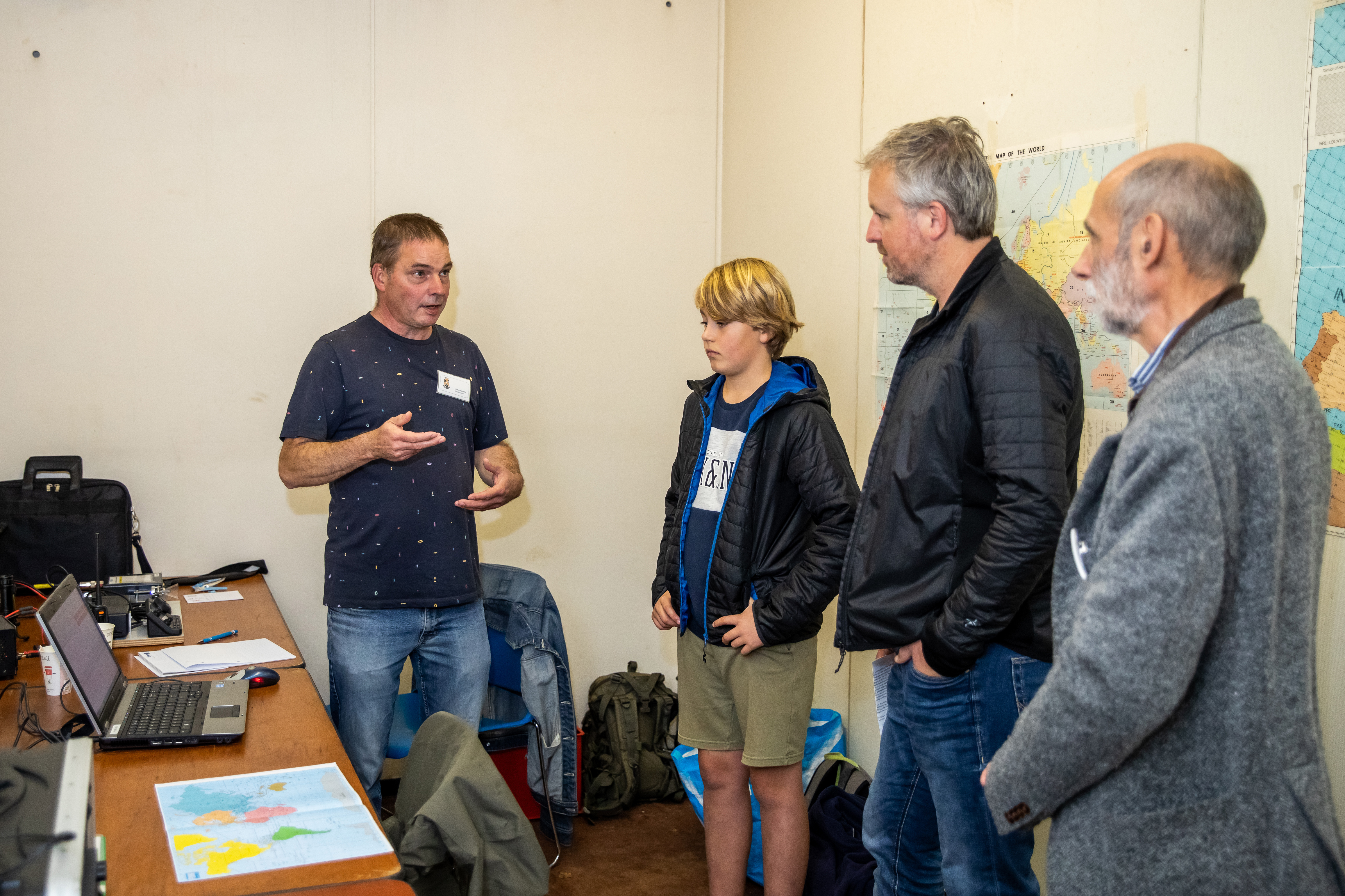 Twee mannen en een kind luisteren naar uitleg van een vrijwilliger in de BB-bunker.