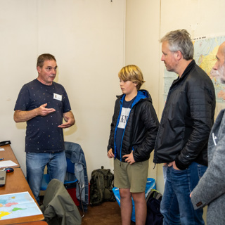 Twee mannen en een kind luisteren naar uitleg van een vrijwilliger in de BB-bunker.