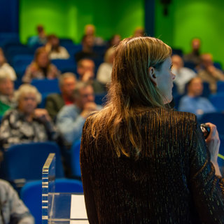 Juanita Kiburg tijdens haar lezing met op de achtergrond de deelnemer van de Zeeuwse Archeologiedag. 