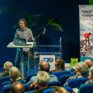 Hans Jongepier van Erfgoed Zeeland vertelt over een mesolitische vindplaats bij Sint-Kruis tijdens zijn lezing met Alex Groosman.