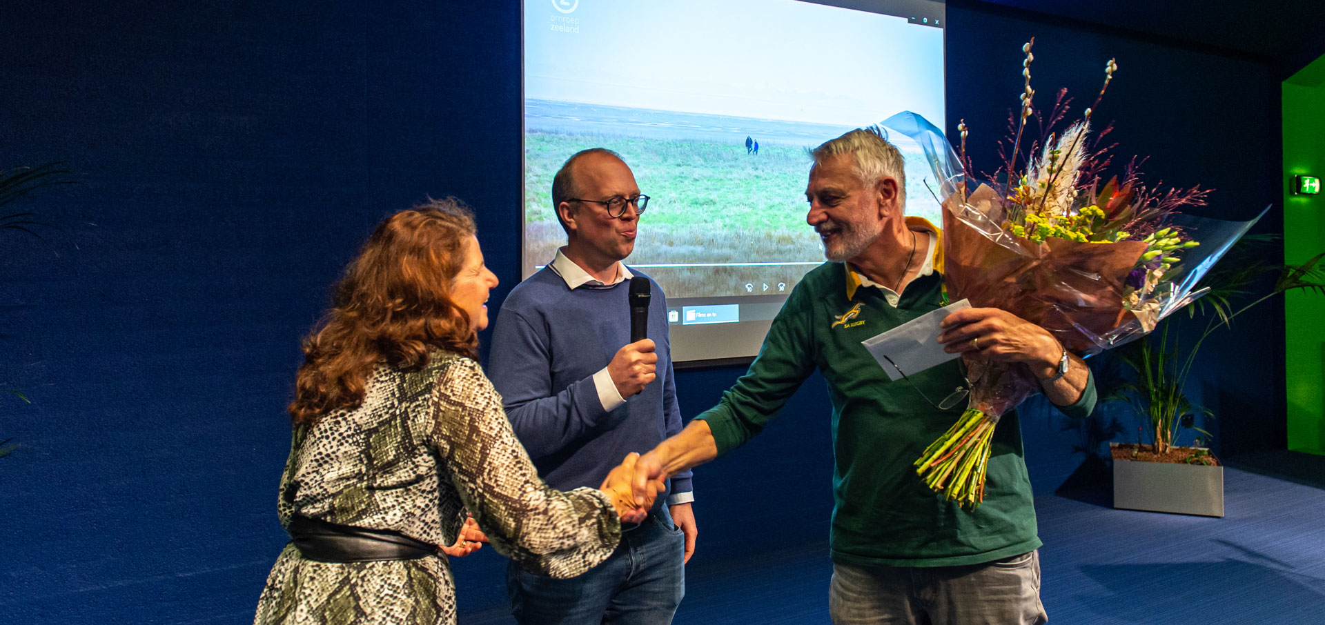 Alex Groosman en Ariane Lafort van de AWN overhandigen een bos bloemen aan Robert van Dierendonck.  