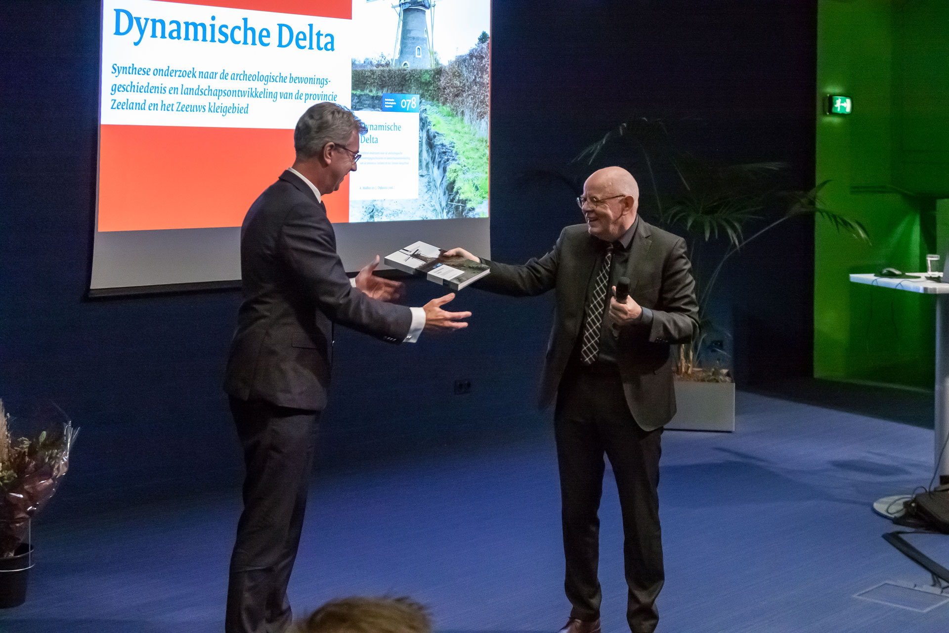 Leonard de Wit van de Rijksdienst voor het Cultureel Erfgoed overhandigt de onderzoekssynthese aan gedeputeerde Harry van der Maas. Foto Niek Beeke.