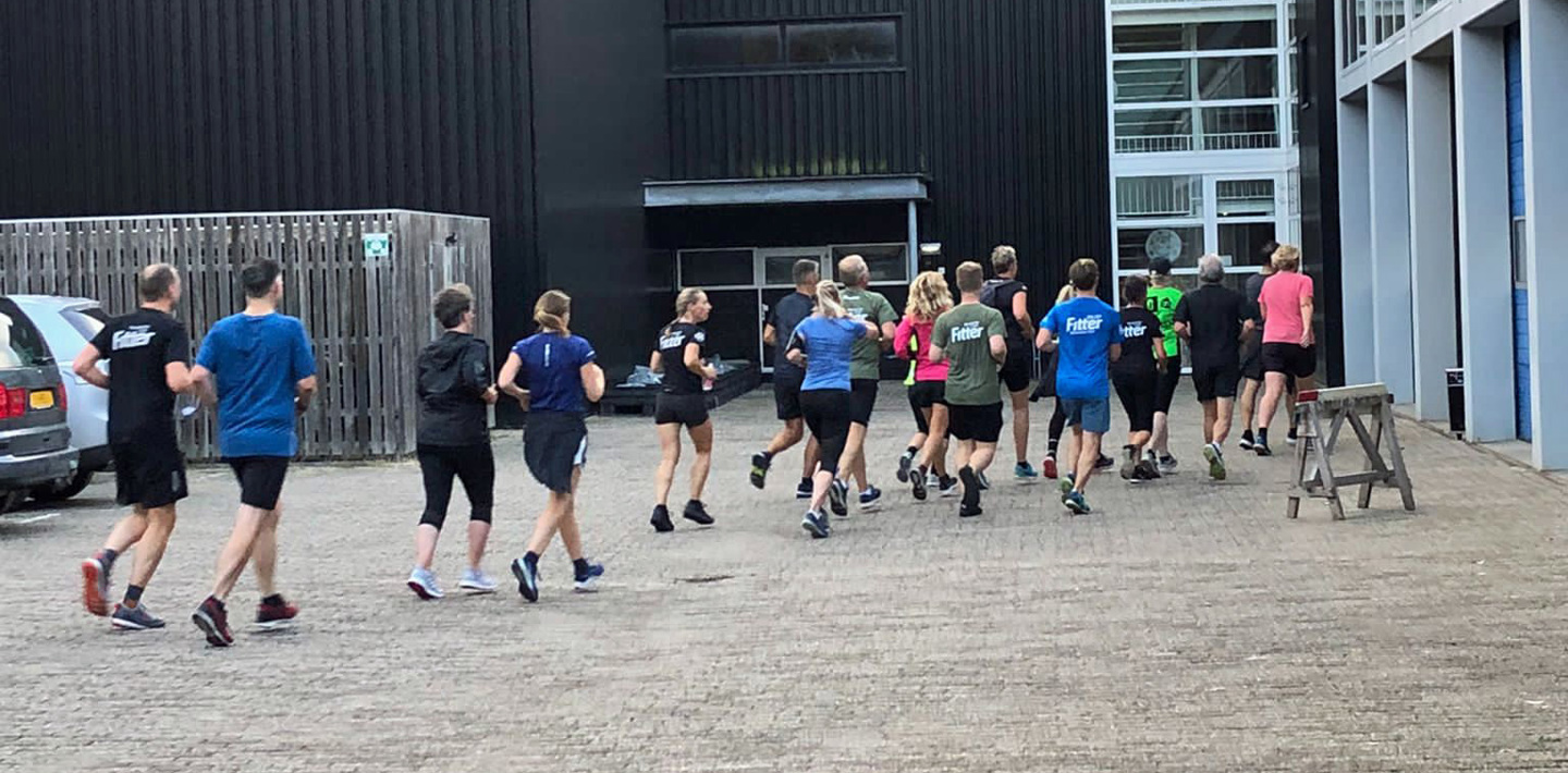 Hardlopers van City Trail Middelburg rennen naar de toegangsdeur van het depot van de Monumentenwacht.