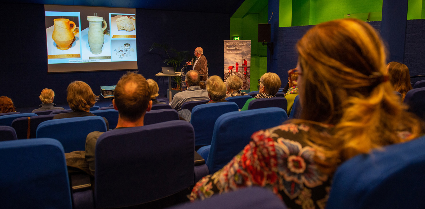 Deelnemers aan de Zeeuwse Archeologiedag 2022 volgen een presentatie van een spreker.