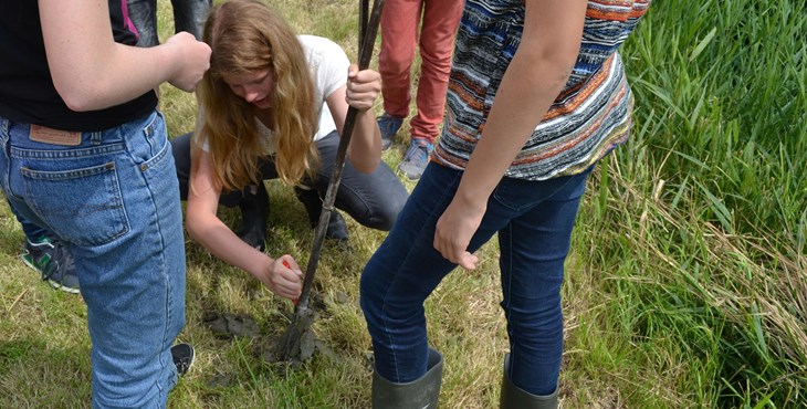 Jongeren volgen de archeologieles 'Het veld in': een meisje probeert een grondboor uit.