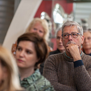 Aanwezigen van de voorjaarsbijeenkomst Reizen in de Tijd luisteren naar een spreker.