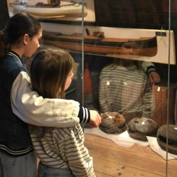 Twee meisjes kijken naar een vitrine met voorwerpen over onderwaterarcheologie in het Maritiem muZEEum Zeeland.