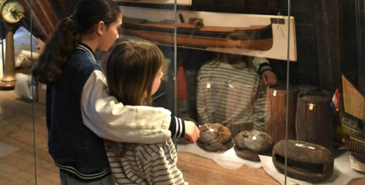 Twee meisjes kijken naar een vitrine met voorwerpen over onderwaterarcheologie in het Maritiem muZEEum Zeeland.