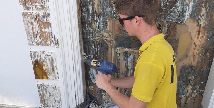 Jesse van Dommele, leerling mbo-opleiding schilderen, bezig met het restaureren van een voordeur.
