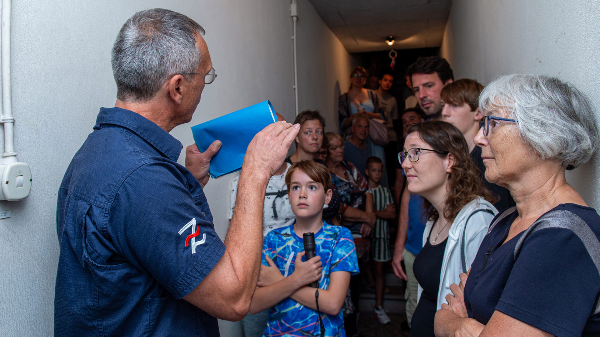 Bezoekers luisteren aandachtig naar uitleg in de lange centrale gang van de ondergrondse BB-commandopost / schuilkelder.