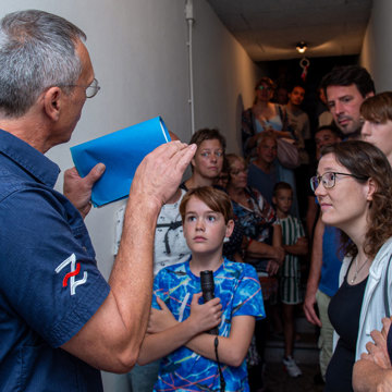 Bezoekers luisteren aandachtig naar uitleg in de lange centrale gang van de ondergrondse BB-commandopost / schuilkelder.
