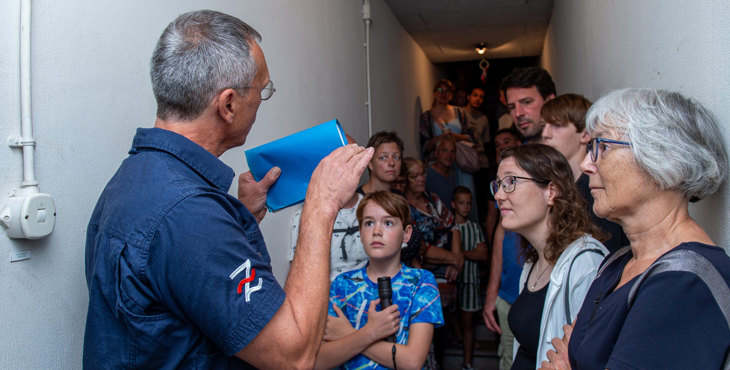 Bezoekers luisteren aandachtig naar uitleg in de lange centrale gang van de ondergrondse BB-commandopost / schuilkelder.