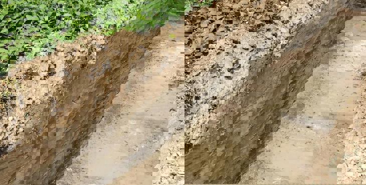 Een in de bodem gegraven proefsleuf voor een archeologisch onderzoek.
