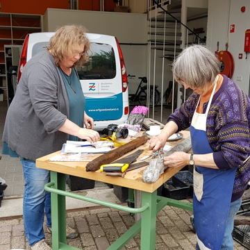 Twee vrijwilligers spoelen opgegraven palen uit Oud Rilland bij Erfgoed Zeeland.