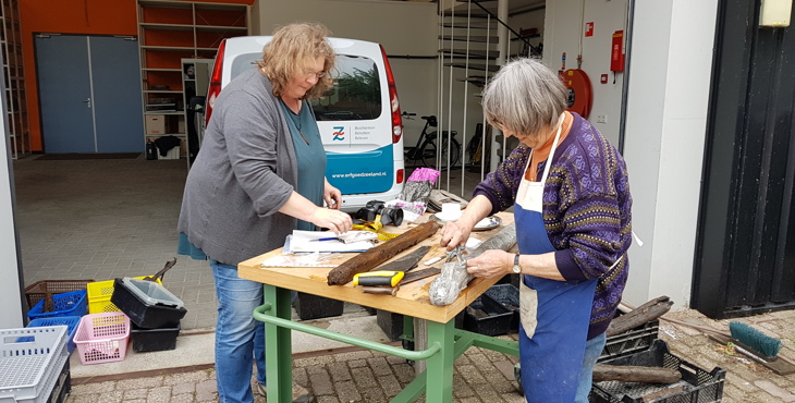 Twee vrijwilligers spoelen opgegraven palen uit Oud Rilland bij Erfgoed Zeeland.