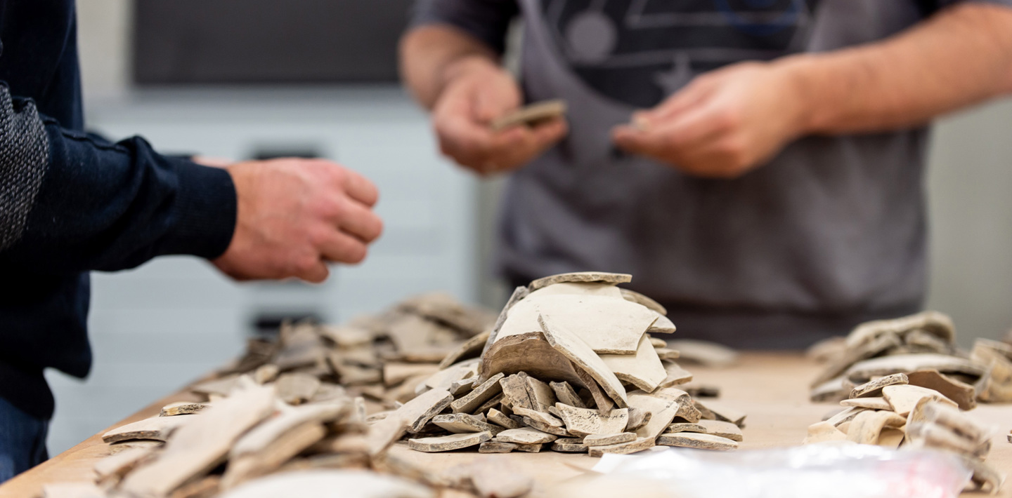 Twee personen bestuderen scherven in het Zeeuws Archeologisch Depot.
