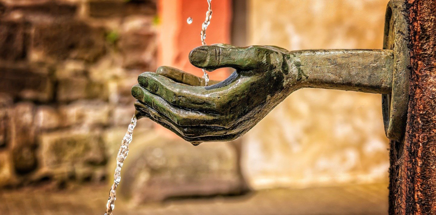 Een fontein die bestaat uit een hand waar het water instroomt.