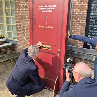 Gedeputeerde Harry van der Maas kijkt door de brievenbus naar een van de parels van Collectie Zeeland.