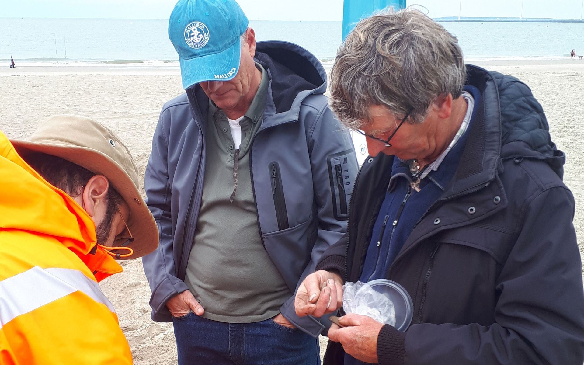 Strandzoekers met elkaar in gesprek over archeologische vondsten op het strand.