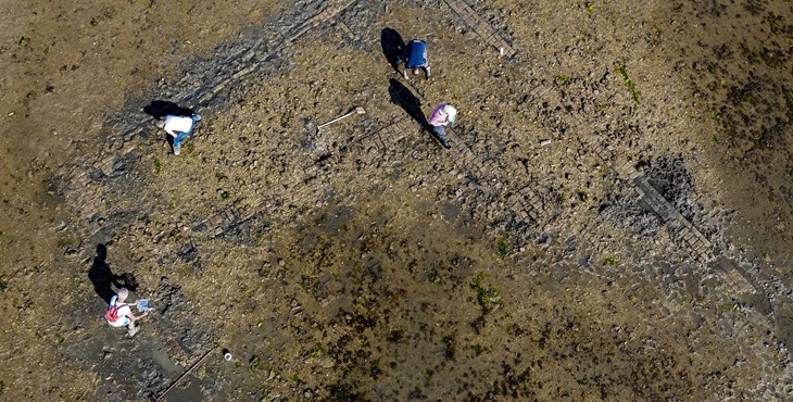 Luchtfoto van het verdronken dorp Tolsende met mensen die de restanten bestuderen