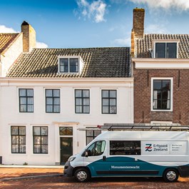 Bus van de Monumentenwacht geparkeerd voor monumentale woonhuizen in Middelburg