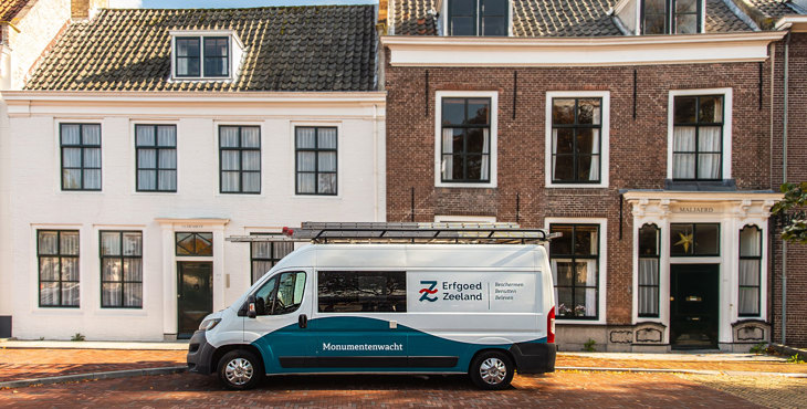 Bus van de Monumentenwacht geparkeerd voor monumentale woonhuizen in Middelburg
