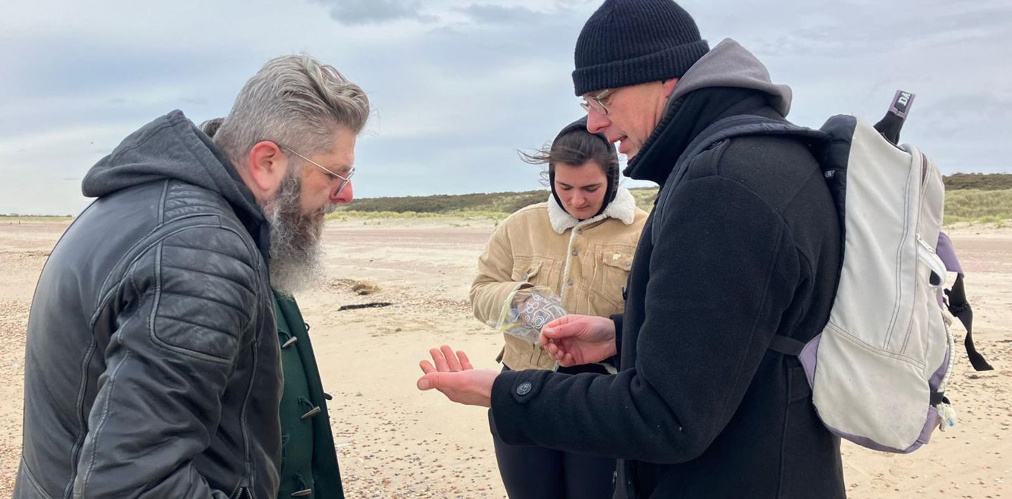 Contactpersonen van OAS Archeologie zoeken naar Romeinse scherven op het strand bij Vrouwenpolder.