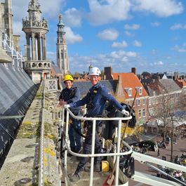 Monumentenwachters Sem de Paauw en Leon Leendertse inspecteren in een hoogwerker het oude stadhuis van Middelburg.