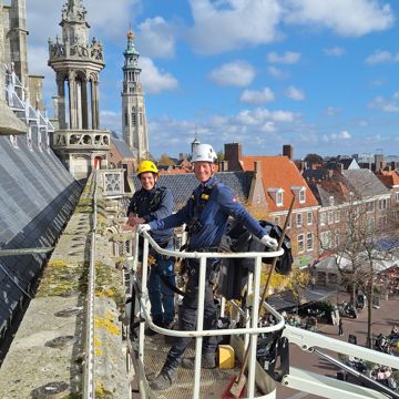 Monumentenwachters Sem de Paauw en Leon Leendertse inspecteren in een hoogwerker het oude stadhuis van Middelburg.