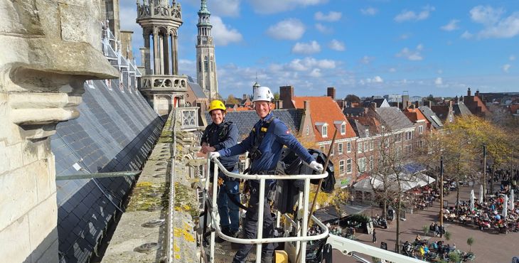 Monumentenwachters Sem de Paauw en Leon Leendertse inspecteren in een hoogwerker het oude stadhuis van Middelburg.