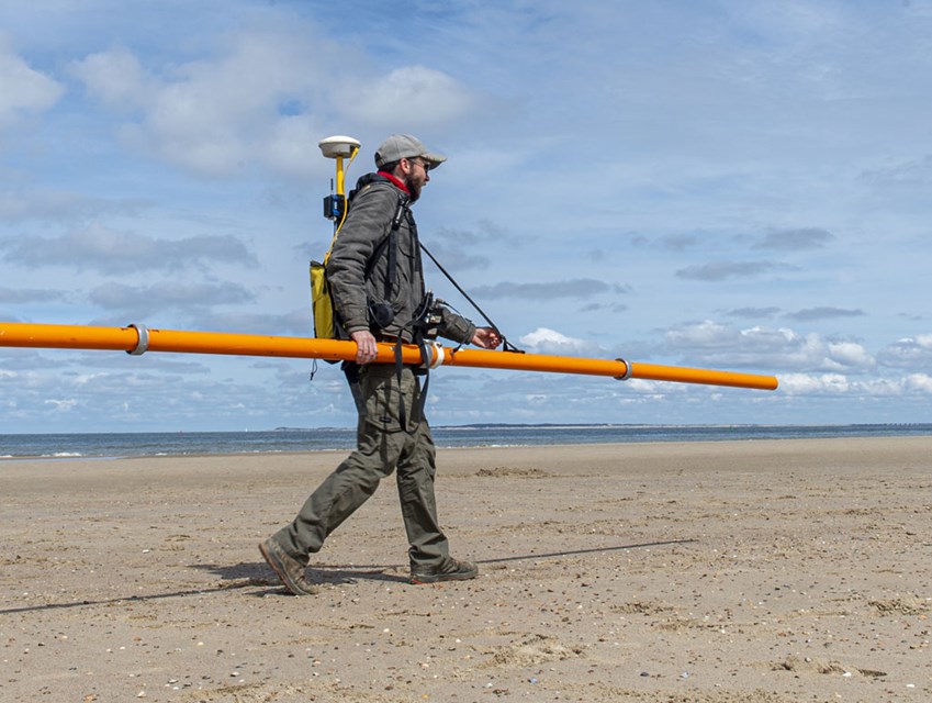 Bodemonderzoek van strand Oranjezon met elektromagnetische meetapparatuur.