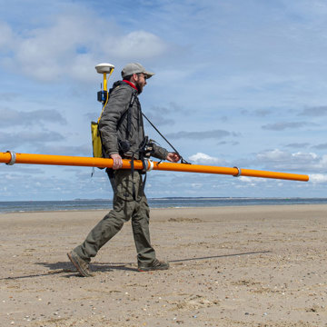 Bodemonderzoek van strand Oranjezon met elektromagnetische meetapparatuur.