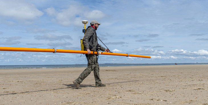Bodemonderzoek van strand Oranjezon met elektromagnetische meetapparatuur.