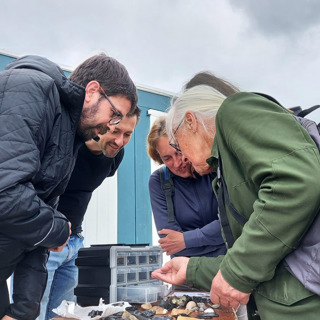 Voorbijgangers bewonderen de fossielen die uitgestald op tafel liggen.