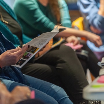 Verschillende deelnemers van een cursus luisteren en bekijken een boekje.