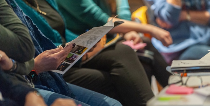 Verschillende deelnemers van een cursus luisteren en bekijken een boekje.